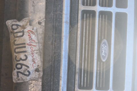 1992 Ford Bronco - A close-up view of a Ford emblem on a vehicle's grille, alongside a weathered California license plate.