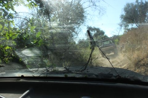 1992 Ford Bronco - Another vehicle navigates a rough off-road trail, kicking up dust.