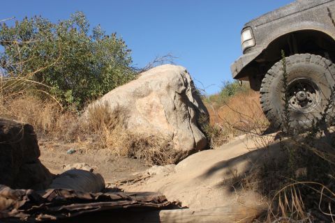 1992 Ford Bronco - A 1992 Ford Bronco navigates a rough, rocky off-road trail under a clear blue sky.