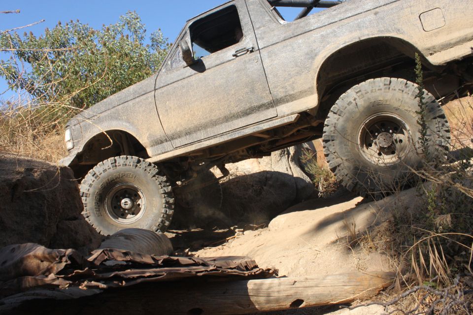 Mud-covered SUV with large tires navigating a rocky trail