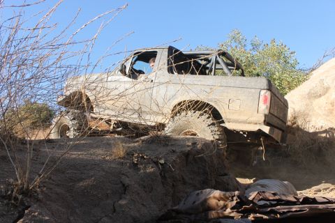 1992 Ford Bronco - A modified off-road vehicle navigates a challenging rocky trail under a clear blue sky.