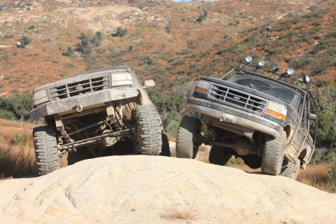 1992 Ford Bronco - Two Ford Broncos navigate a challenging off-road trail with steep inclines and rocky terrain.