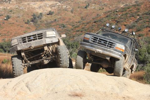 1992 Ford Bronco - Two modified 1992 Ford Broncos navigate a challenging off-road trail, demonstrating their climbing capabilities.