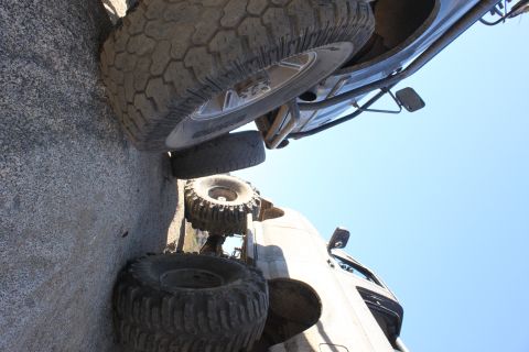 1992 Ford Bronco - Multiple off-road vehicles are positioned on a rocky surface with a bright blue sky overhead.