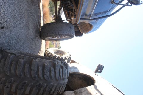 1992 Ford Bronco - A vehicle with oversized tires is positioned on a rocky, uneven surface, showing its undercarriage and suspension.