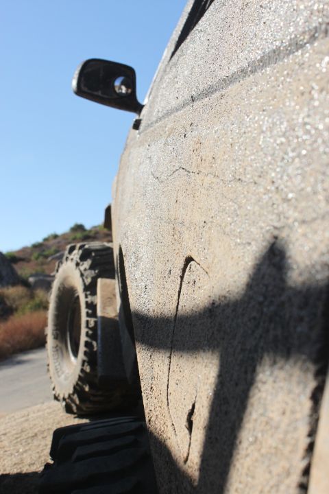 1992 Ford Bronco - Side view of a heavily mud-splattered vehicle with large off-road tires.