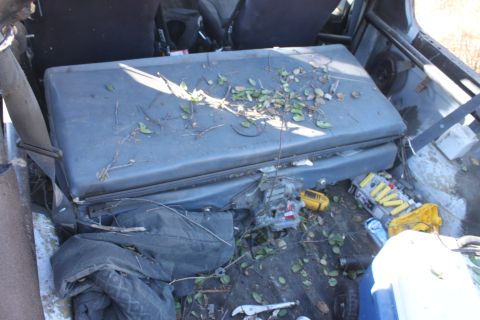 1992 Ford Bronco - The interior of a vehicle is filled with debris, including leaves, tools, and a yellow case.