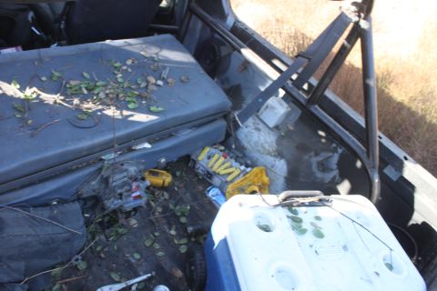 1992 Ford Bronco - The interior of a vehicle is cluttered with a cooler, tools, and leaves, suggesting recent use or storage.