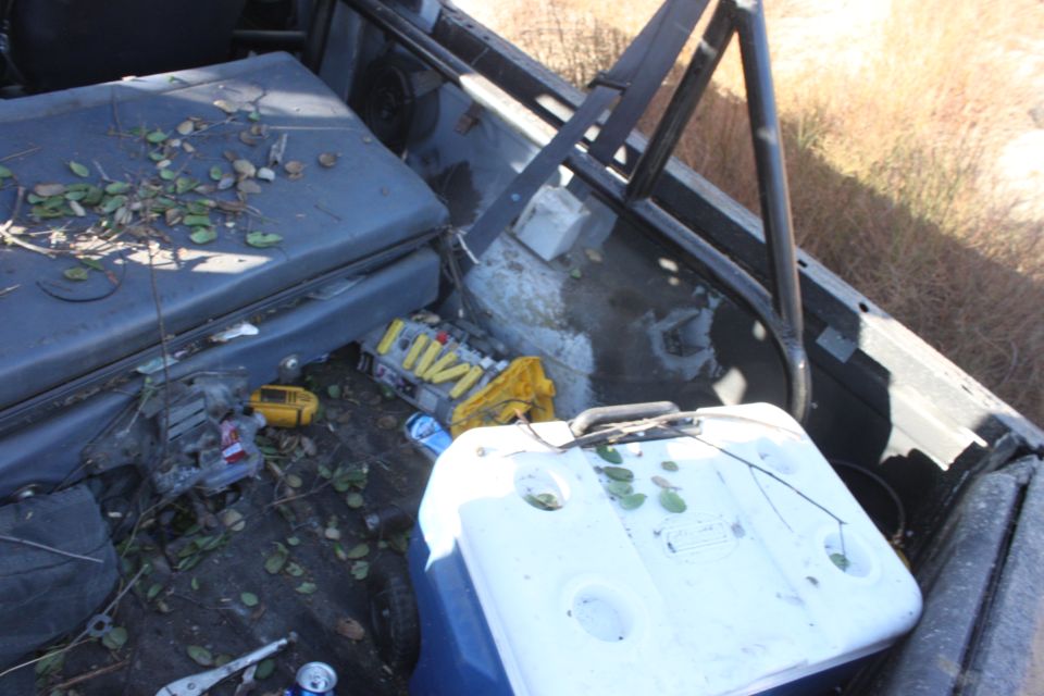 1992 Ford Bronco interior with a white cooler, yellow tool case, and scattered leaves