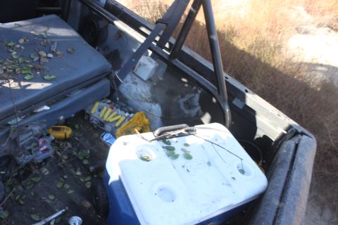 1992 Ford Bronco - A cooler and various supplies are visible in the bed of a vehicle, with a roll bar overhead.