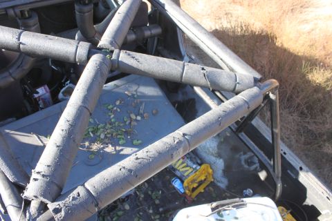 1992 Ford Bronco - The interior of a vehicle shows a complex roll cage structure and scattered debris on the floor.
