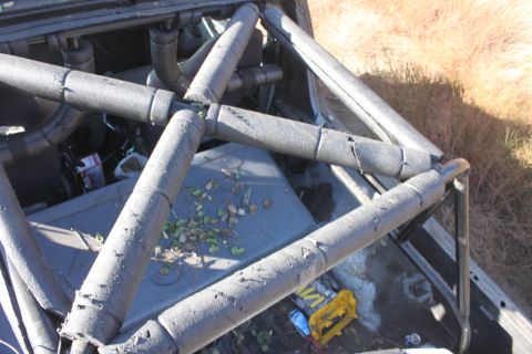 1992 Ford Bronco - The interior of a vehicle is visible, a prominent roll cage with foam padding and debris on the floor.