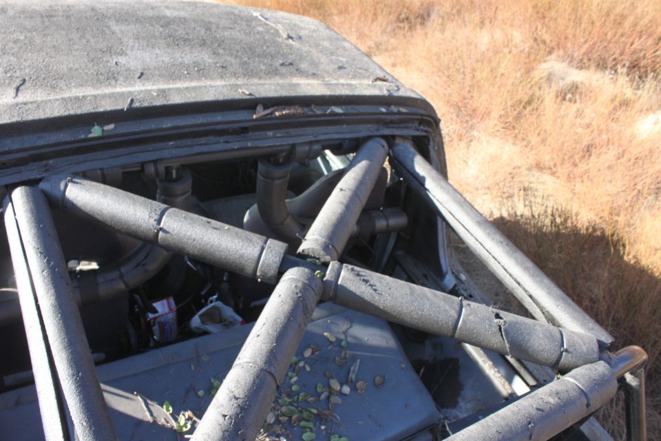 Interior of a vehicle with a roll cage, showing some engine components and debris on the floor