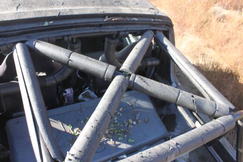 1992 Ford Bronco - The interior of a damaged vehicle shows a complex roll cage structure and exposed engine parts.