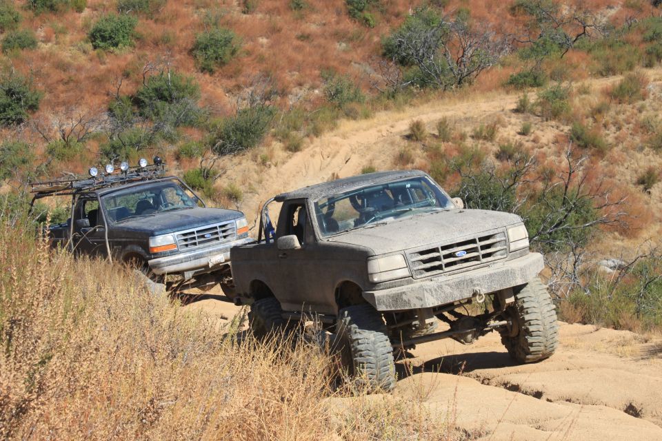 Mud-covered 1992 Ford Bronco with lifted suspension and off-road tires, angled right on a dirt trail