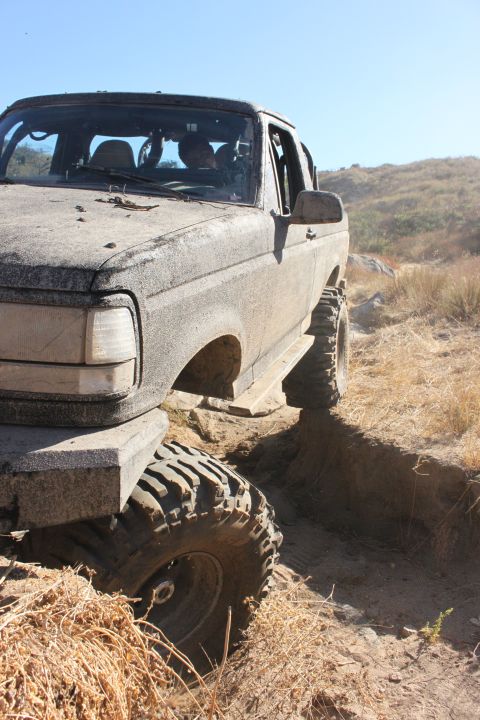 1992 Ford Bronco - This 1992 Ford Bronco is shown off-road, covered in mud and tackling a challenging trail.