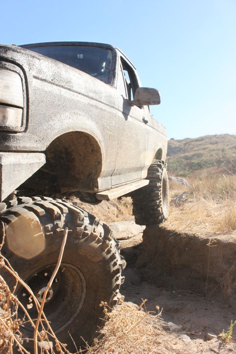 1992 Ford Bronco - This heavily soiled vehicle navigates a challenging off-road terrain with large, aggressive tires.