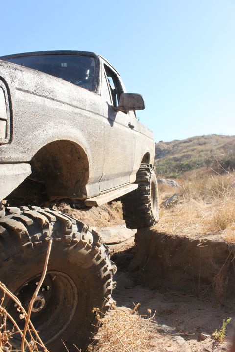 1992 Ford Bronco - A heavily modified 1992 Ford Bronco navigates a challenging off-road trail with steep inclines.