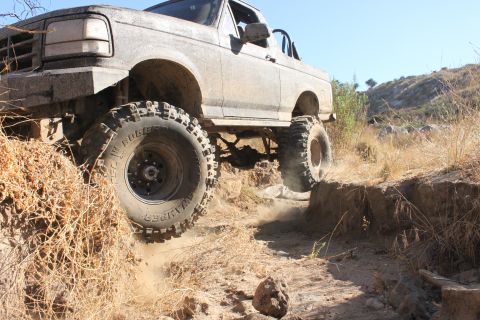 1992 Ford Bronco - This 1992 Ford Bronco navigates a challenging off-road trail, kicking up dust as it climbs.