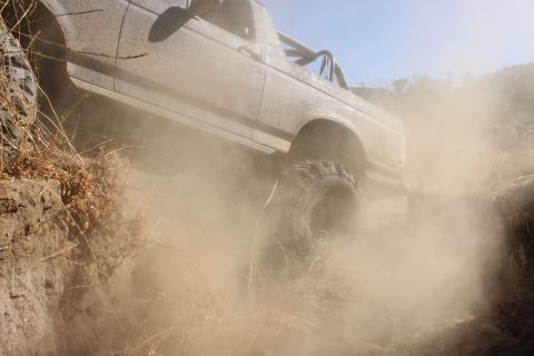 1992 Ford Bronco - A 1992 Ford Bronco kicks up dust as it navigates a rough off-road path.