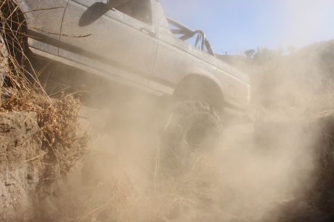 1992 Ford Bronco - This 1992 Ford Bronco navigates a dusty, off-road trail with significant dust clouds billowing.