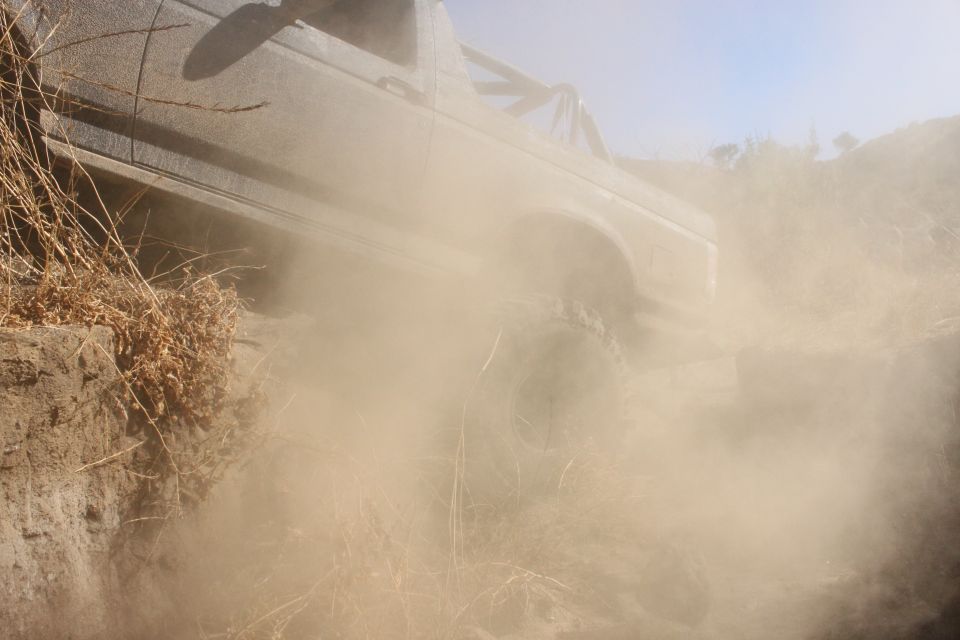 1992 Ford Bronco kicking up dust while driving off-road