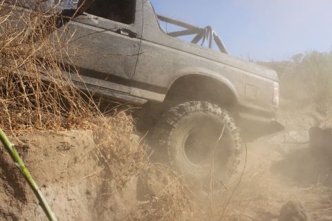 1992 Ford Bronco - A 1992 Ford Bronco navigates a dusty, off-road trail with steep inclines.