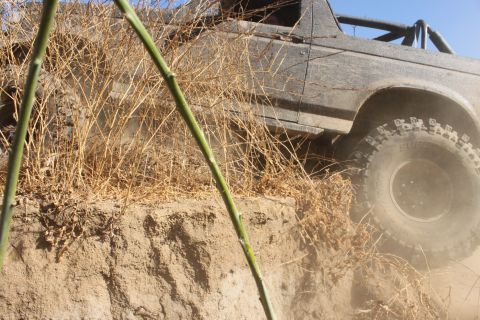 1992 Ford Bronco - A vehicle navigates a steep dirt incline, with dry brush obscuring the view.