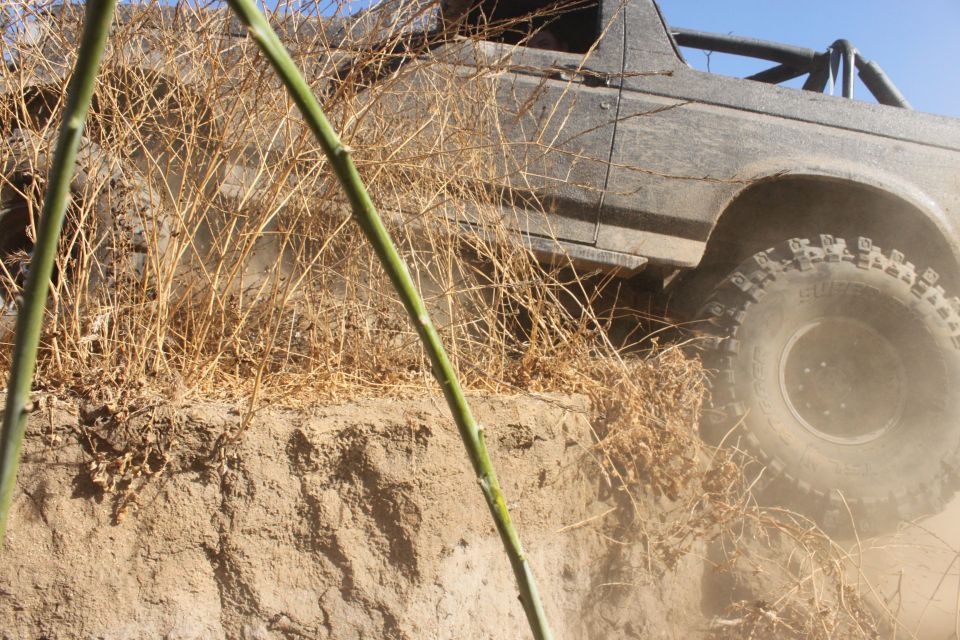 off-road vehicle climbing dirt bank, tire kicking up dust