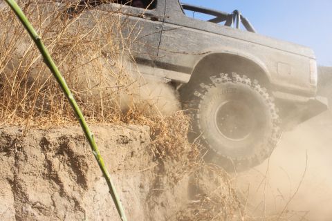 1992 Ford Bronco - A vehicle navigates a challenging off-road terrain, kicking up dust.