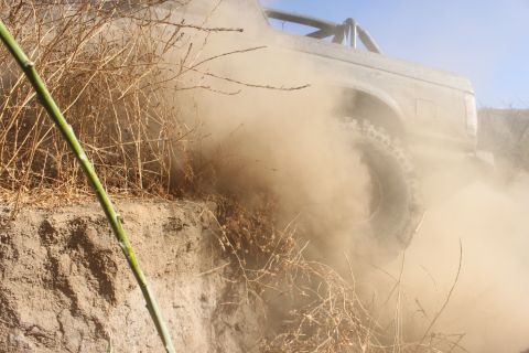1992 Ford Bronco - Ford Bronco navigates a dusty trail, its tires kicking up a significant amount of dirt.