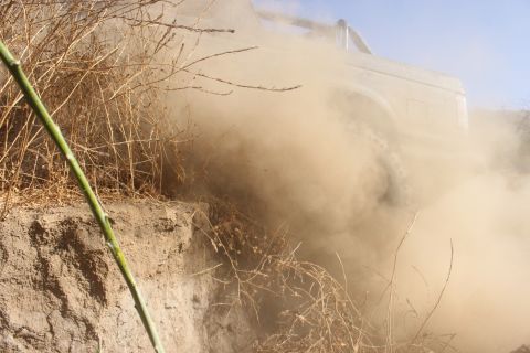 1992 Ford Bronco - A vehicle navigates a dusty, off-road trail, obscured by a cloud of dirt.