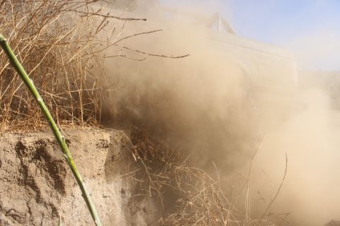 1992 Ford Bronco - Vehicle driving off-road, obscured by dust and dry vegetation.