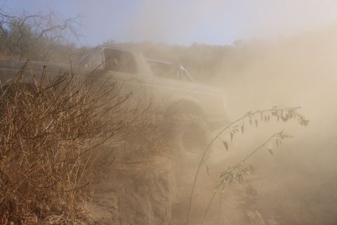 1992 Ford Bronco - A vehicle navigates a dry, dusty trail, obscured by the dust it's creating.