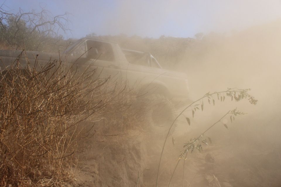 Truck driving on a dusty trail, kicking up a lot of dust