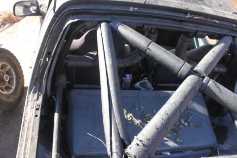 1992 Ford Bronco - The interior of a vehicle is visible, a complex roll cage structure with padded bars.