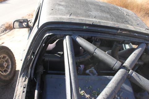 1992 Ford Bronco - Interior view of a modified off-road vehicle, showing a prominent roll cage and dusty dashboard.
