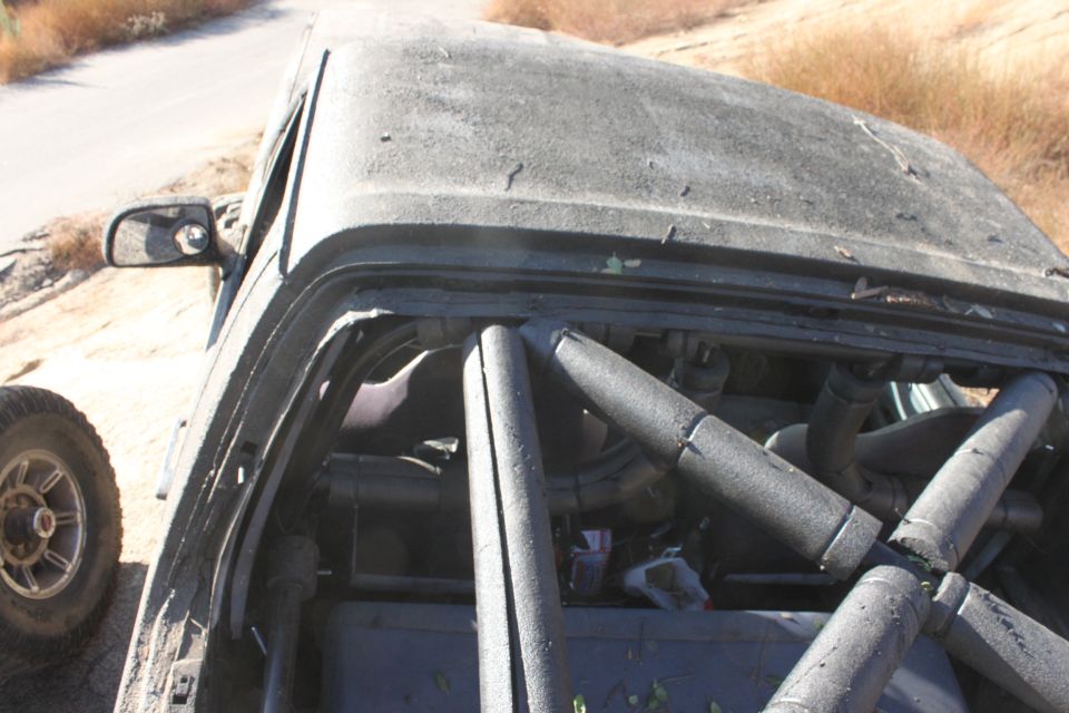 Dark gray 1992 Ford Bronco interior with roll cage, dusty exterior, side view