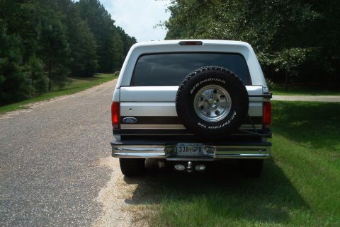 1992 Ford Bronco - Rear view of a silver 1992 Ford Bronco, showing the spare tire mounted on the tailgate and a chrome bumper.