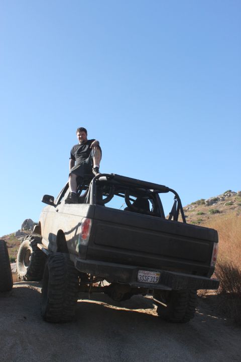 guy sitting on roof of lifted off-road truck, sunny day