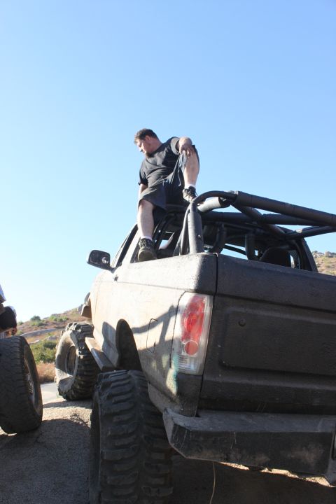 Man on top of a lifted off-road vehicle, rear view