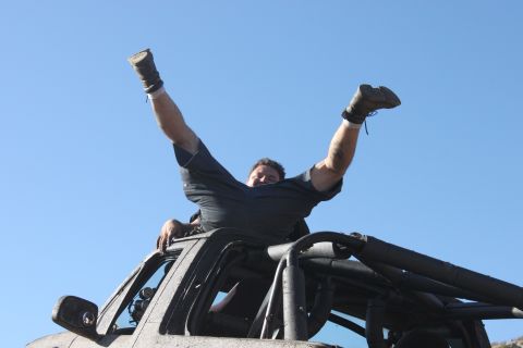 Guy with arms and legs up in the air on top of a roll cage