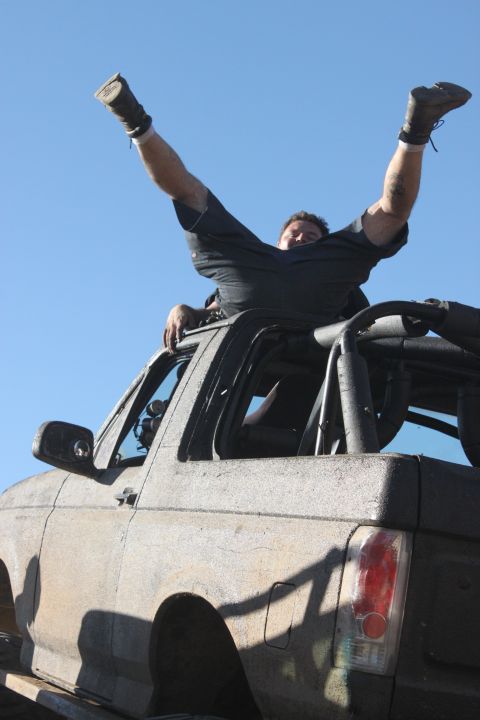 Dirty 1992 Ford Bronco with a man on top, viewed from the front-right