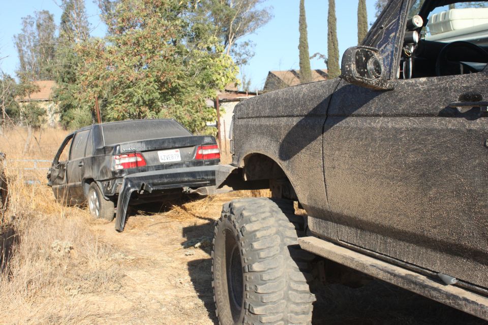 Black sedan towed by lifted truck with large tires