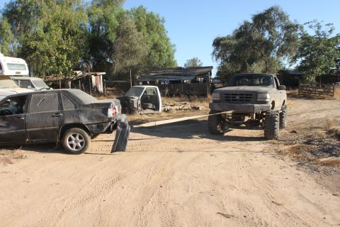 Gray 1992 Ford F-Series truck with large tires towing a dark sedan