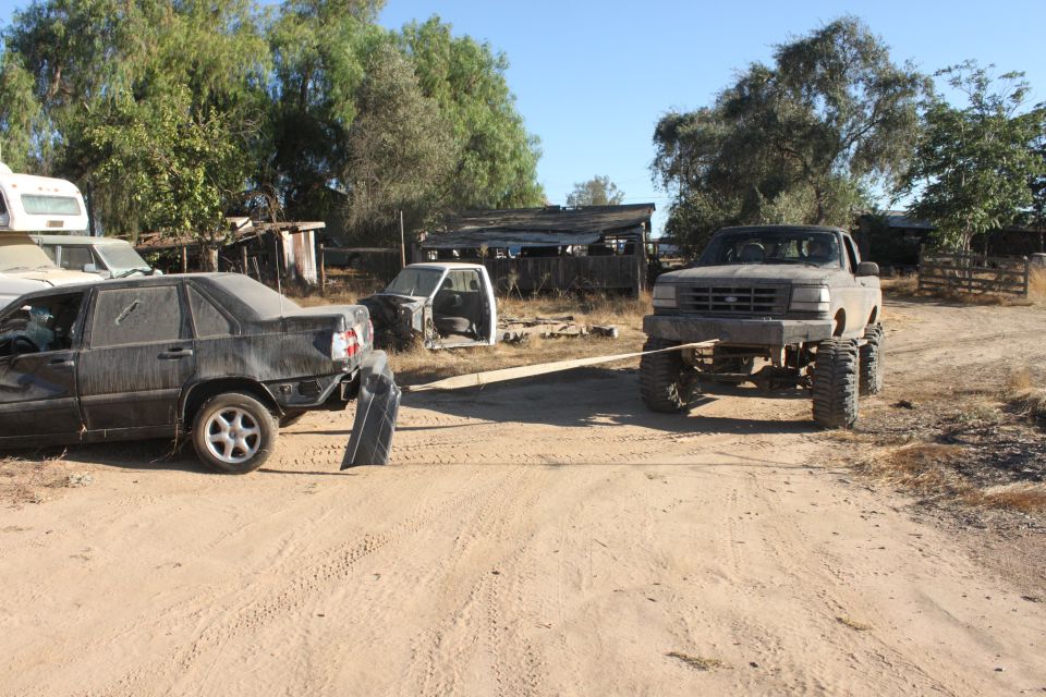 Gray 1992 Ford F-Series truck with large tires towing a dark sedan