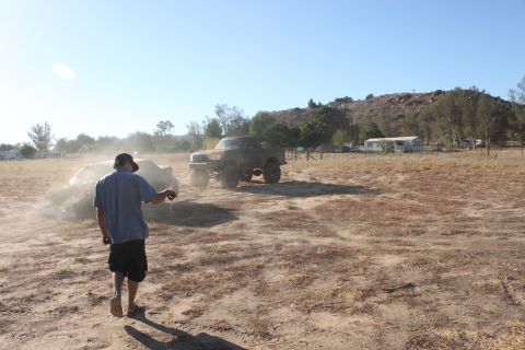 Brown lifted truck being towed in a dry, dusty field