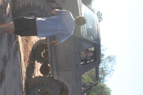 Side view of a heavily modified off-road vehicle with large tires and a person in the driver's seat