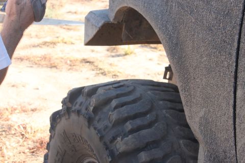 Close-up of a large off-road tire and a dusty fender flare