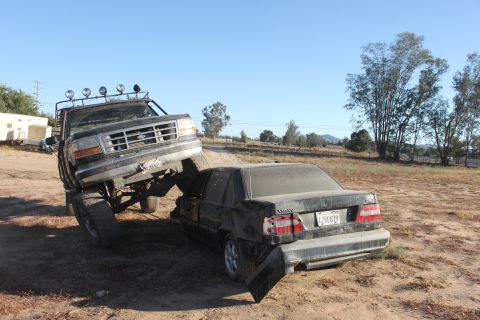 1992 Ford F-Series truck on a wrecked Volvo sedan in a dirt lot